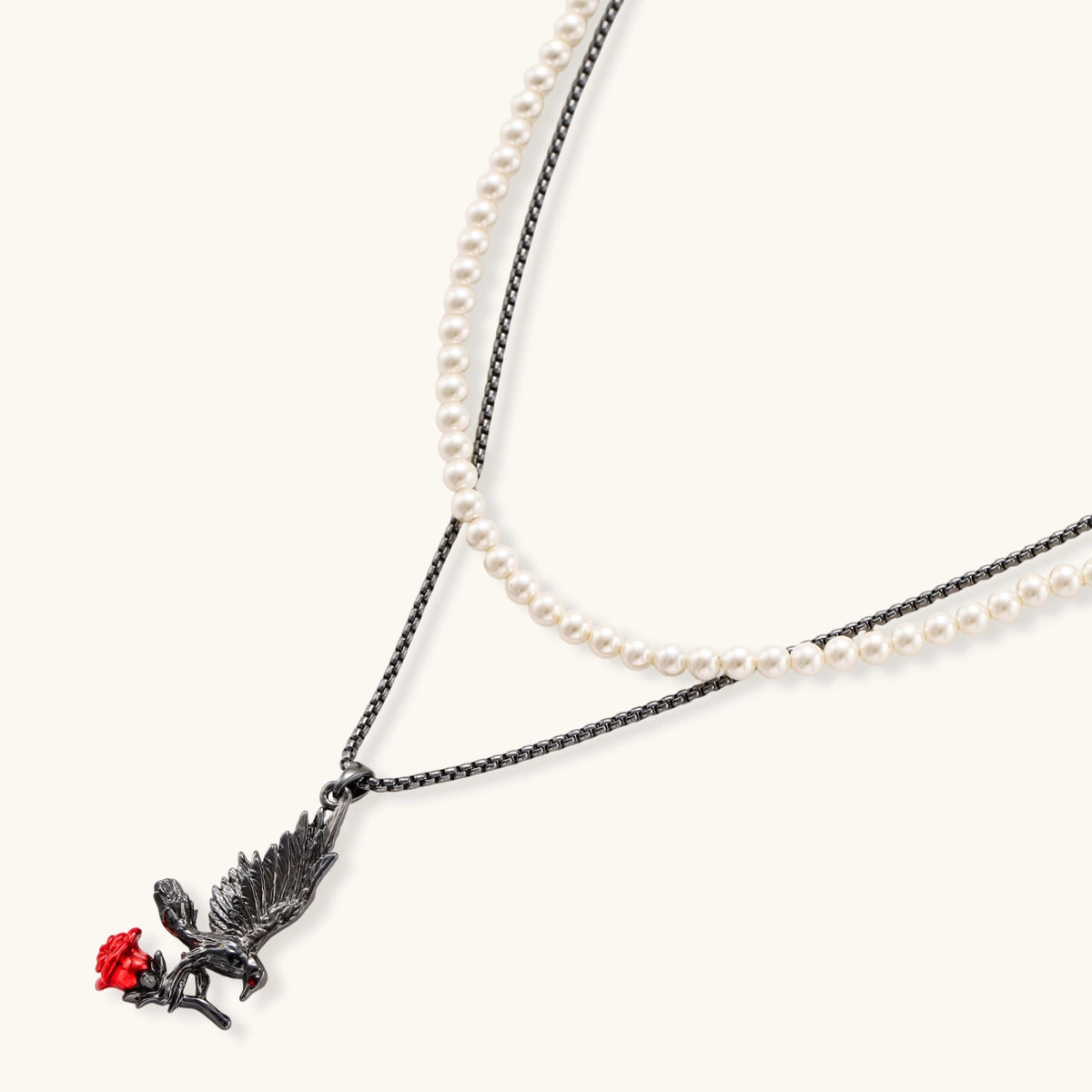 Dark gunmetal jewelry set featuring detailed raven pendants carrying red enamel roses with layered pearl and chain necklaces