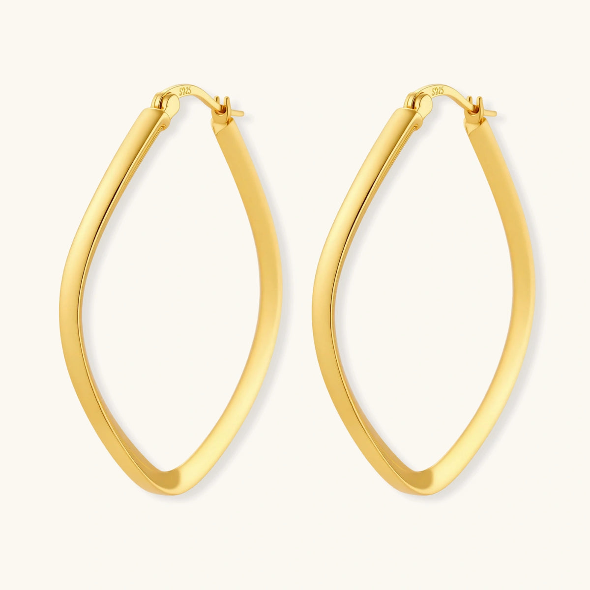 Set of geometric gold-plated sterling silver hoop earrings in oval and cushion shapes on cream background